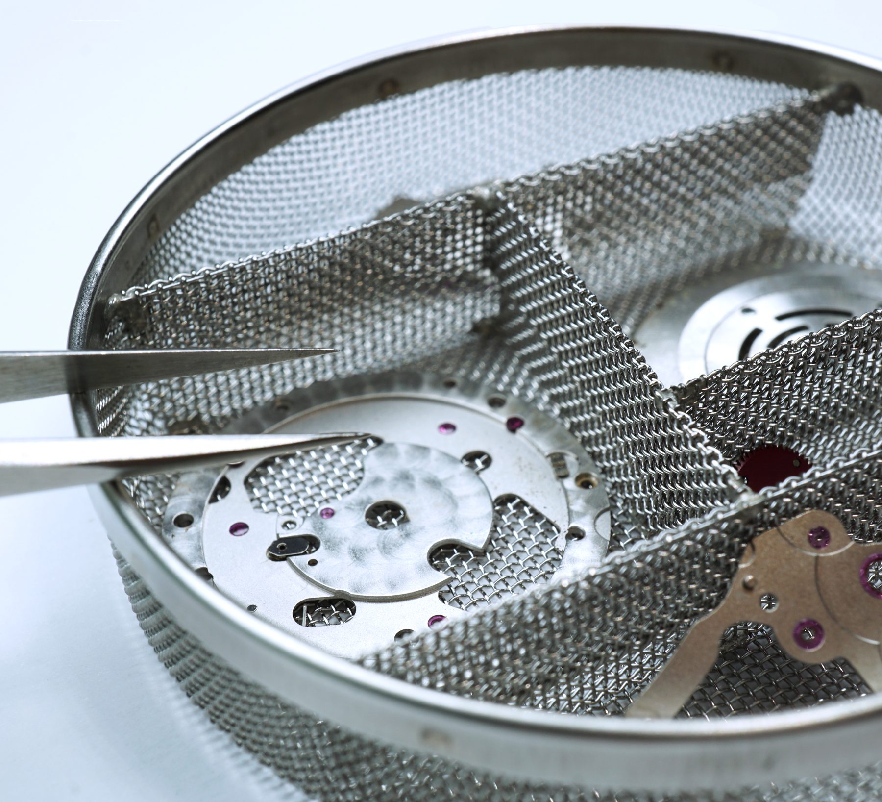 Watch movement parts in a cleaning basket